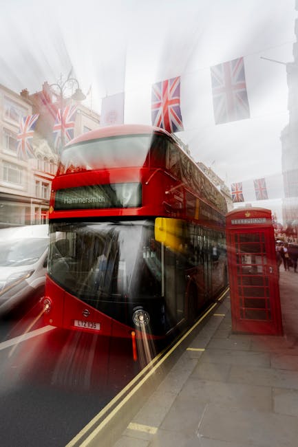 A red double-decker bus displaying the route number 9 and the destination 'Hammersmith' travels along a busy city street, surrounded by pedestrians, storefronts, and historic buildings. The scene incl