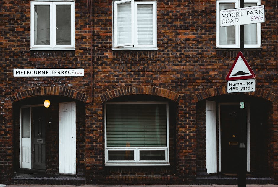 This image shows the front facade of a brick residential building located on Melbourne Terrace, SW6, with two white-framed windows on the upper floor and two doors on the ground level, each beneath a